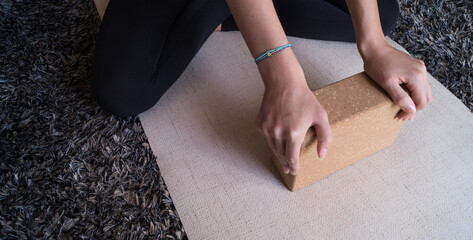 Practising yoga with a block on a beige mat