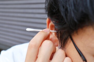 日本人男性が綿棒で耳掃除をしている