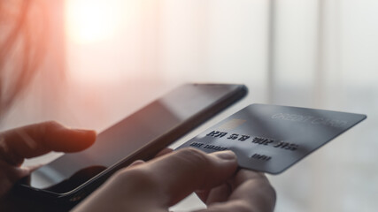 Woman hands holding a blue credit card selective focus on card number and using a smartphone for shopping online or internet banking. Online shopping concept.