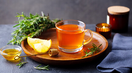 Tea cup with rosemary, honey and lemon. Grey background. Copy space.