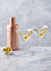 Martini cocktail with olives and bar shaker. Marble background. Copy space.