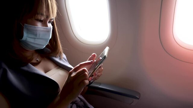 Close up hand of Young business woman Using smartphone on an Airplane.,woman wearing face mask on an airplane travel concept new normal background.during coronavirus or covid-19 virus outbreak