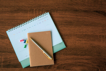 The top view blank calendar with a pen on desk office for copy space composition