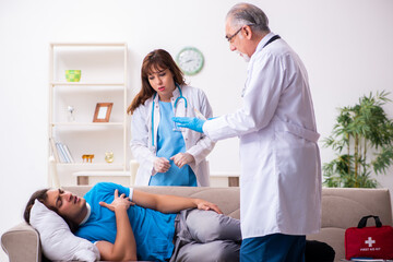 Obraz premium Two doctors visiting sick young man at home
