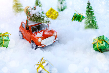 Christmas tree on red car toy with blurred tree background and snow.