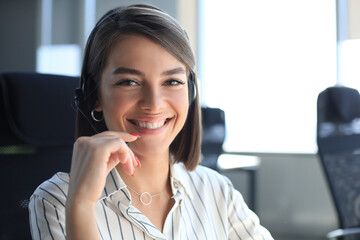 Female customer support operator with headset and smiling.