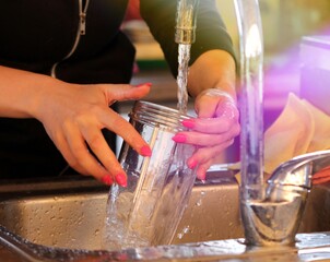 close up gesture of hands washing a glass on a sink using detergent and water image