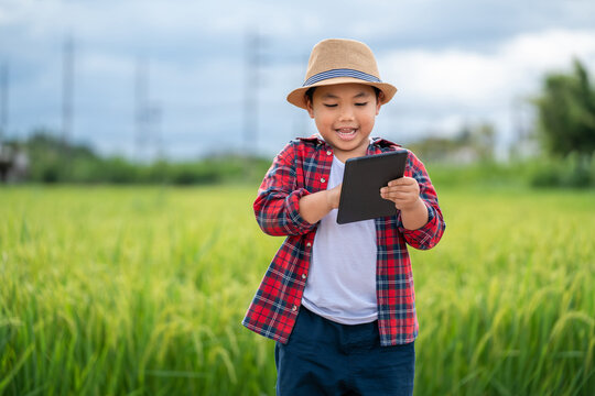 Asian Little boy watching and touchpad tablet in learning the surroundings in the green fields in the age of technology, education concept outside the classroom Educational freedom