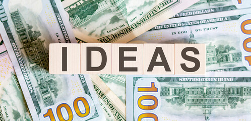 Concept words IDEAS on wooden blocks on a beautiful background from dollar bills.