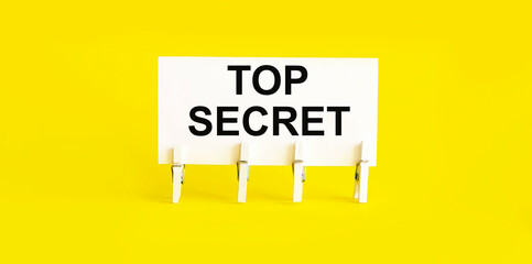 text TOP SECRET on white short note paper yellow background