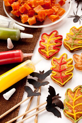 Cookies in the shape of leaf decorated with bright writing icing. Decorations for Halloween party