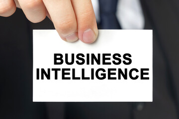 Businessman shows a card with the text - BUSINESS INTELLIGENCE