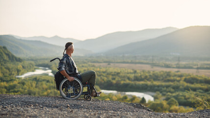 Athlete after serious injury in wheelchair enjoy fresh air in the mountains. Rehabilitation of...