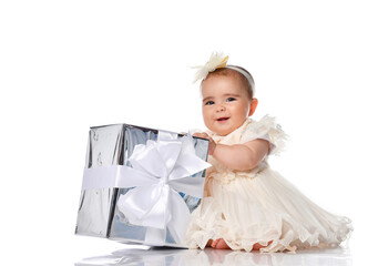 Little baby girl holding a big gift box in her hands on a white background.