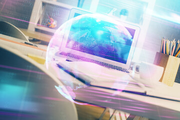 Computer on desktop in office with technology theme hologram. Double exposure. Tech concept.