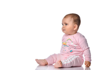Naklejka premium Child sits sideways looks away and smiles on a white background.