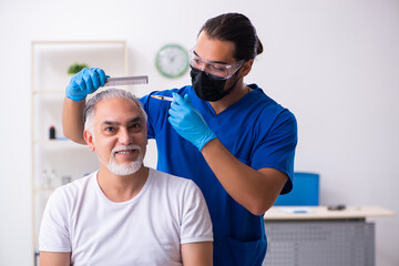 Obraz premium Old man visiting young male doctor in hair transplantation conce