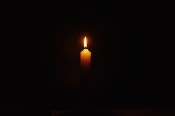 Fototapeta premium Burning candle Wick from a candle in a flame of fire. Symbol of sadness and loneliness. A time of condolences. Burning wax candle. Religion.