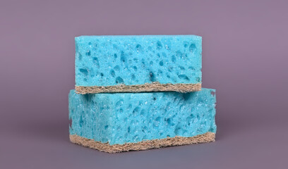 A porous blue washcloth for cleaning the apartment and washing dishes on a gray background.