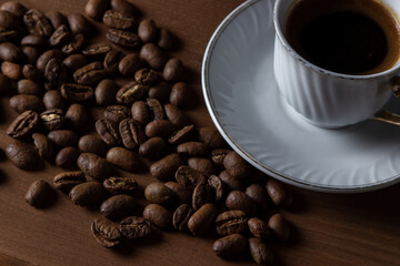 A cup of boiled coffee, coffee beans are next to it.