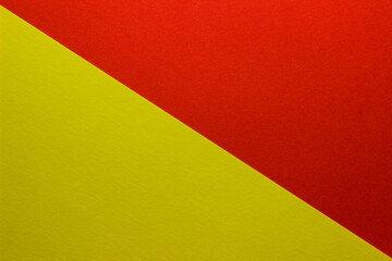 Background of red and yellow paper divided diagonally. Sheets of blank yellow and red paper with fine texture, close up.