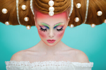 Closeup portrait of a female model with a creative colorful makeup and hairstyle with huge pearls....