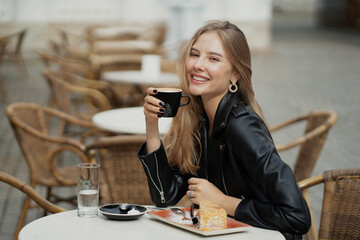 a Cup of delicious aromatic hot coffee is held in the hands of a charming confident blonde woman of...