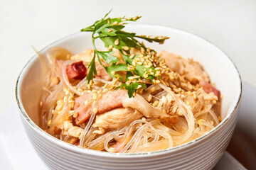 Cellophane noodles with chicken and bacon in a light plate