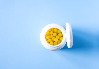 The plastic container of pills on bright blue background.