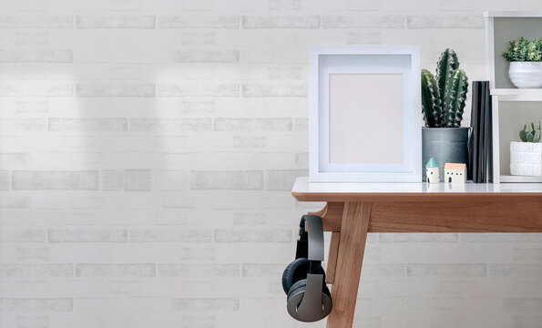Mockup white wooden picture frame with green plant on white top table in contemporary room, copy space.