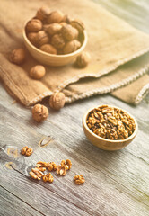 Fresh walnut kernels and whole walnuts in a bowl on rustic old wooden table. Healthy organic food, BIO viands, natural background. Copy space for your advertising text message