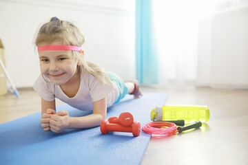 Sport and healthy lifestyle.Child playing sports at home. Yoga mat dumbbell and jump rope. Sports background home exercises concept.