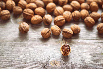 Heap of whole walnuts and one walnut kernel on wooden table - natural pattern background detail. Close up of brown surface texture. Healthy organic food, BIO viands, back to nature concept
