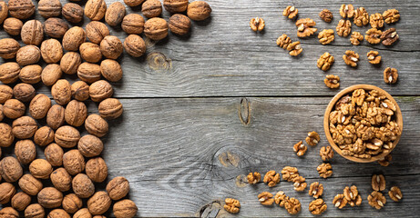Fresh walnut kernels and whole walnuts in a bowl on rustic old wooden table. Healthy organic food, BIO viands, natural background. Copy space for your advertising text message