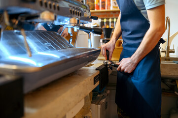 Male barista in apron prepares coffee on machine