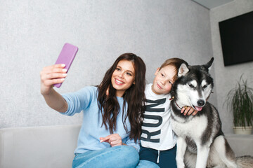 Mother and little son taking a selfie with dog at home