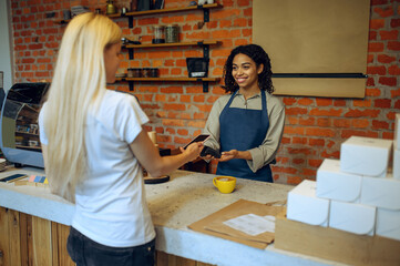 Male barista in cafe, customer pays for the order