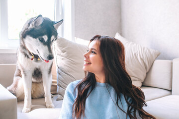 Happy woman with a beautiful husky dog at home © Elena Kratovich