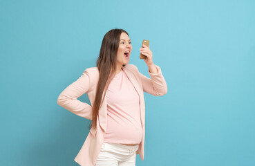 frightened young pregnant woman on blue background calls by mobile phone, discharge of amniotic fluid, the beginning of labor process