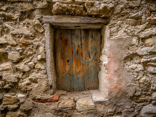 Fototapeta na wymiar opening in an old stone wall, closed by a colored shutter
