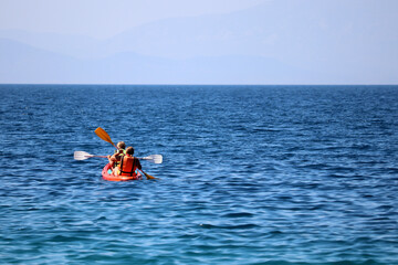 Kayaking in the sea, two girls with paddles sitting in canoe. Travel and water sports concept