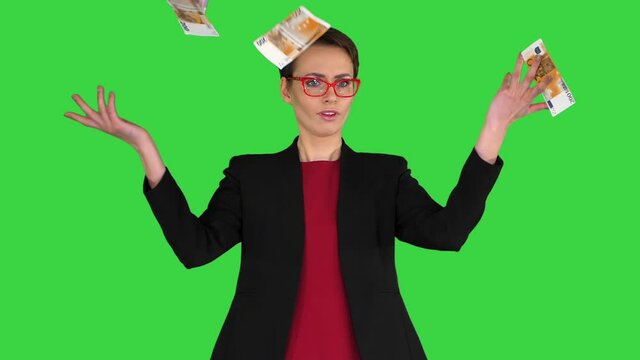 Business Woman In Glasses Tossing Money In The Air On A Green Screen, Chroma Key.