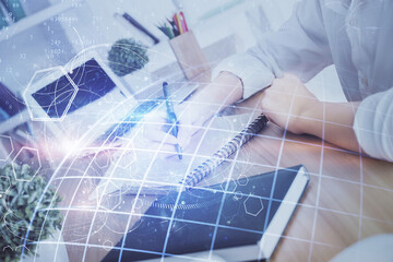 Double exposure of hands making notes with world map hologram and data theme icons. Concept of international network data.