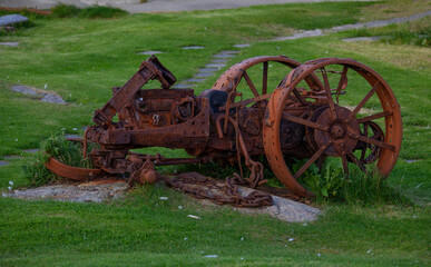 rusty wreck of a primitive tractor displayed on a lawn