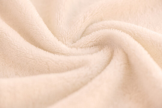 A soft cozy plaid made of white fabric with a pile lies in beautiful folds