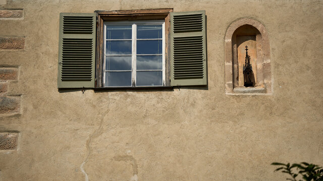 Old cloister window with wooden sashes, small arched niche with sculpture.