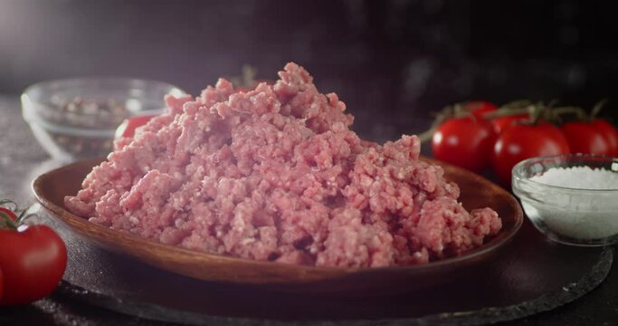 A wooden plate with raw minced meat rotates slowly. 