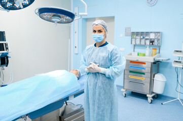 Surgeon in gown, mask and gloves in operating room
