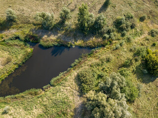 Fototapeta na wymiar Small lake among green meadows. Summer sunny day. Aerial drone view.