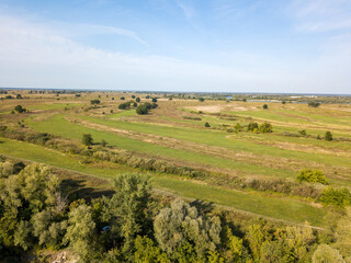 Fototapeta premium Dirt road among green meadows. Summer sunny day. Aerial drone view.